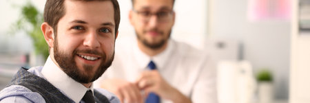 Portrait of smiling businessmen in shirts and ties sitting together during a meeting at the...