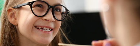 Close up of smiling cute little girl looking at the doctor before checking throat in the clinicの写真素材
