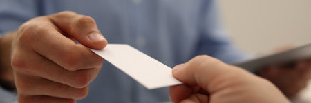 Close up of man giving a business card to his male colleague after meeting. Business negotiations conceptの写真素材