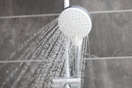 Shower mixer from which water flows into bathroom. Contrast shower benefits for the body conceptの写真素材
