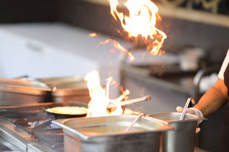 Cook is cooking on stove with an open fire. Chef training concept