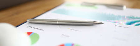 Close-up of paper with monthly report and colourful diagrams and charts. Silver pen laying on document. Calculations and numbers. Business and accountant analysis conceptの写真素材