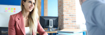 Portrait of stylish young woman in presentable pink suit talking to client. Well dressed female...