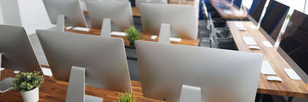Many silver monitors stand on a wooden table in office closeup. Programmer professional education...