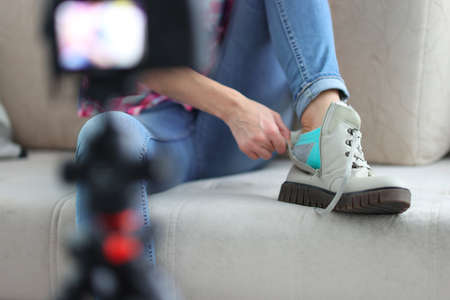 Blogger is filming an overview of boots. Vision blog social media concept