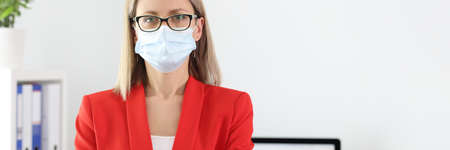 Portrait of businesswoman in medical protective mask and and suit in office. The new reality of...
