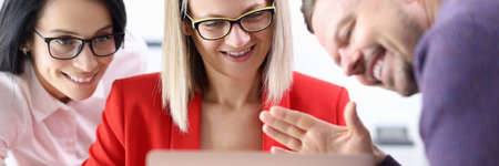 Two women and man waving to other at laptop screen in office. Online business consultations conceptの写真素材