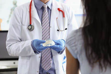 Pastic surgeon demonstrates a silicone implant to patient. Breast augmentation surgery conceptの写真素材