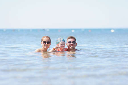 Man, woman and child swim in sea. Family travel with kids conceptの写真素材