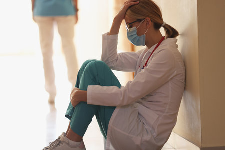 Frustrated doctor sits in hospital corridor. Medical error and accident conceptの写真素材