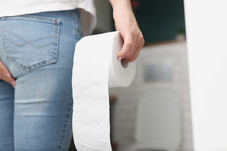 Man stands in front of toilet and holds toilet paper. Encopresis Concept Symptomsの写真素材