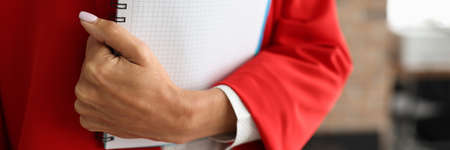 Woman in red suit is holding workbook. Professional business coaching concept.の写真素材
