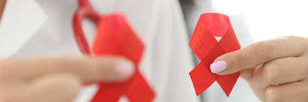 Doctors in white coats hold red ribbon in their hands. Methods for diagnosing HIV infection conceptの写真素材