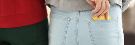 Two people stand with their backs, one takes out condom from a pocket. Safe sex rule concept