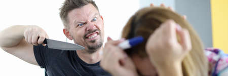 Angry husband threatens to stab his wife with pregnancy test in apartment. Domestic violence in family concept.の写真素材