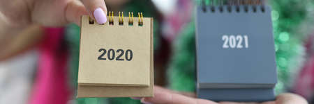 Female hands holding calendars 2020 and 2021 closeup. Production and printing of desktop calendars...