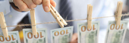 Mans hand of businessman attaches fmerican dollars to rope with clothespins close-up. Business money laundering concept.の写真素材