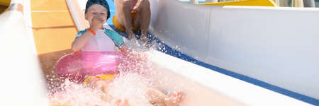 Funny dad and daughter ride water slides. Family spend time at aquapark.