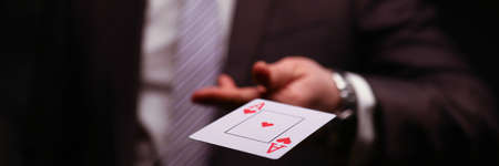 Man in business suit catche red ace playing card. Owning gambling business, maintaining casino and slot machine hall. Illusionist demonstrate trick.の写真素材