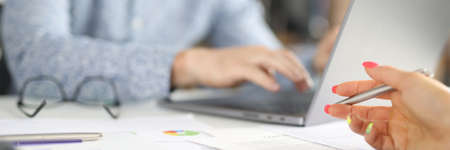 Workplace in office man sits behind laptop female hand holds pen over commercial charts. Small and...