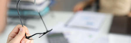 Male hand holds glasses on background of desktop in office. Strategic business planning and teamwork conceptの写真素材