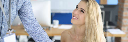 Businesswoman smiles at her colleague and birches his document. Positive communication between business partners conceptの写真素材