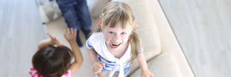 Boy and girls laugh and jump on couch at home. Home games for children concept