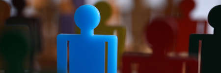 Blue plastic human figure stand out from many plastic dark figures of person. Success and team...