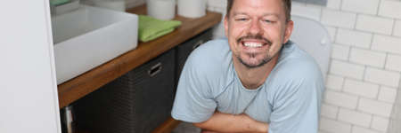 Man with emotion of relief sit on toilet with diarkey. Professional treatment for indigestion and constipation.の写真素材