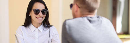 Woman and man are talking at table next to laptop. Meeting in public places conceptの写真素材