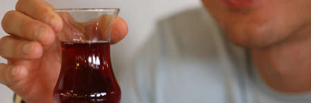 Mans hand holds glass of dark liquid in his hands. Treatment for alcoholism concept