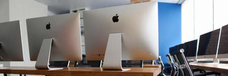 Minsk, Belarus - 30 July 2020: Many silver monitors for business people standing on wooden table in empty office closeup. Illustrative editorialのeditorial素材