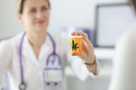 Doctor holding jar of marijuana pills closeup. Drug addiction treatment conceptの写真素材
