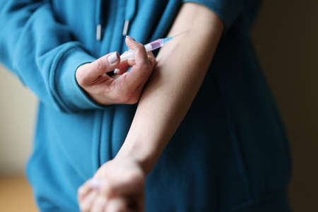 Woman making herself intravenous drug injection closeup. Heroin addiction conceptの写真素材