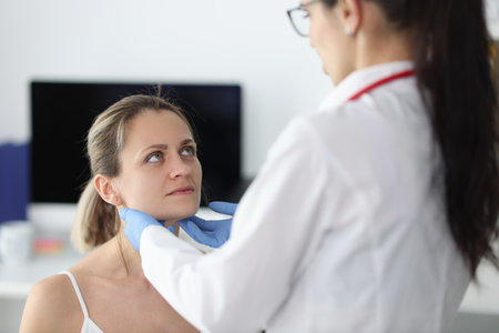 Doctor examining patients submandibular lymph nodes in clinic. Patient examination conceptの写真素材