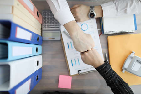 Businessmen touching their fists at table top view. Profitable partnership work conceptの写真素材