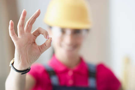 Smiling woman builder holds thumbs up in gesture okの写真素材