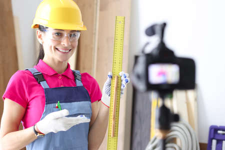 Woman builder demonstrates ruler on video cameraの写真素材