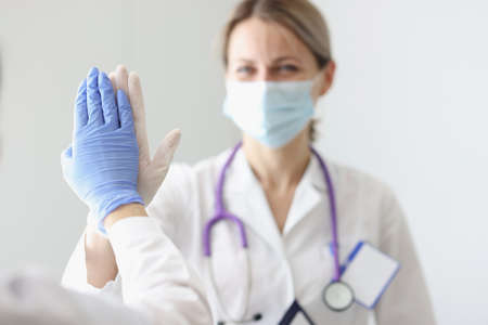 Two doctors in protective masks and gloves give each other fiveの写真素材
