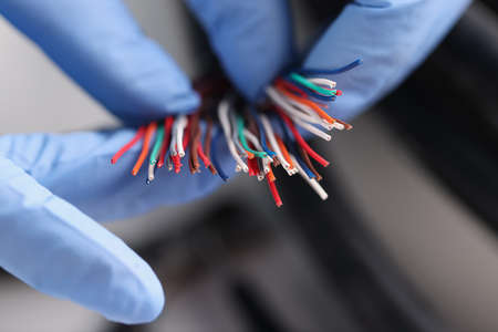 Gloved master holds colored electronic wires closeupの写真素材
