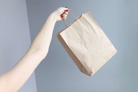 Womans hand holding paper shopping bag closeupの写真素材