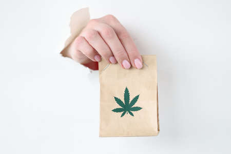 Hand pulling out paper bag of marijuana from torn paperの写真素材