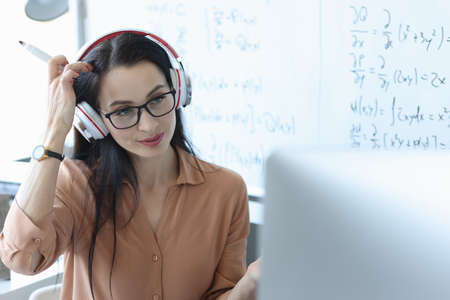 Teacher with headphones on his head looking at laptop screenの写真素材