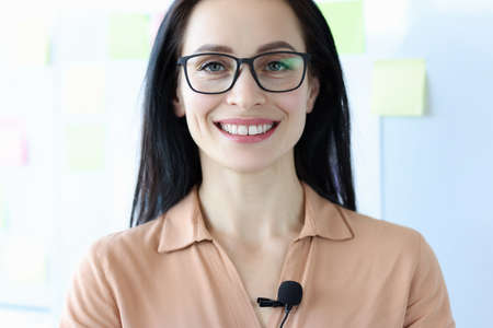 Portrait of smiling woman in glasses with microphone on blouseの写真素材