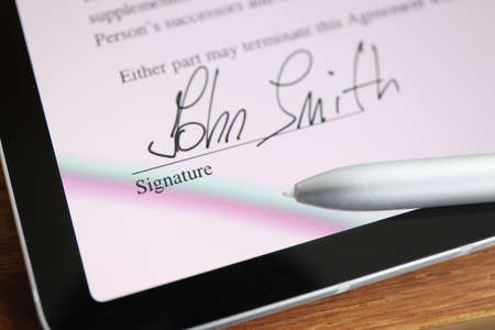 Stylus writing signature on digital tablet closeup