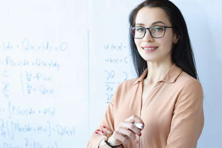 Woman teacher with glasses stands near white board