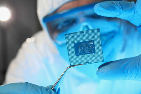 Scientist developer in protective suit holds microcircuitの写真素材