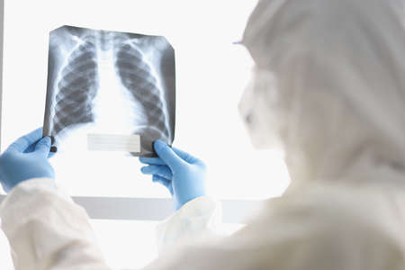Doctor in protective suit examines X-ray closeup