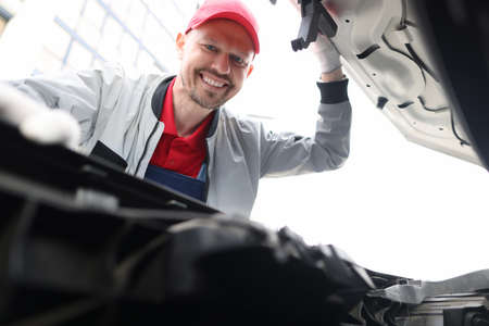 Man repairman looking under hood of carの写真素材