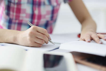 Woman hand writing with ballpoint pen in notebook closeup